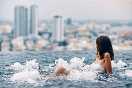 Young woman relaxing in hot tub on the rooftop of hotel and enjoying city viewの写真素材