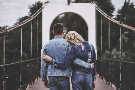 Back view of hugging couple staying on the bridge and enjoying restの写真素材