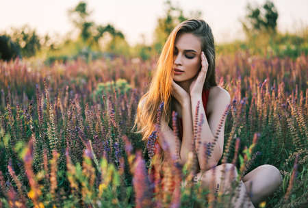 Portrait of beautiful young woman posing in sage field in summer sun