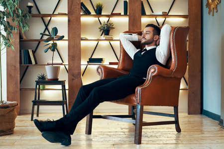 Confident young man relax in armchair in luxury interiorの写真素材