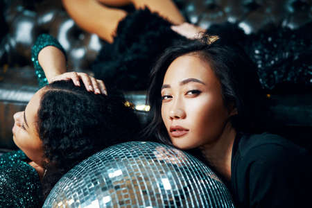 Pretyy women relax and lying down on the floor on disco ball in nightclub after crazy partyの写真素材