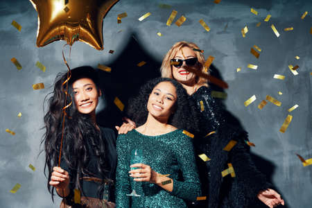 Pretty multiethnic young women have fun together celebrating with confetti on partyの写真素材