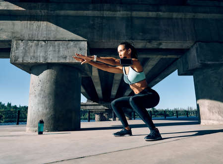 Sporty woman practicing squat exercises outdoors. Sport concept