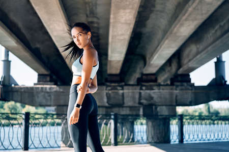 Beautiful confident woman in sportswear posing outdoors. Beauty and sport concept