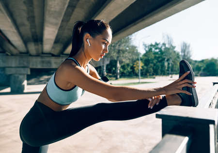 Sporty woman runner stretching legs for warming up before exercising. Urban workout and running conceptの写真素材