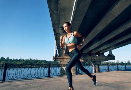 Young fitness woman running at riverside. Healthy lifestyle