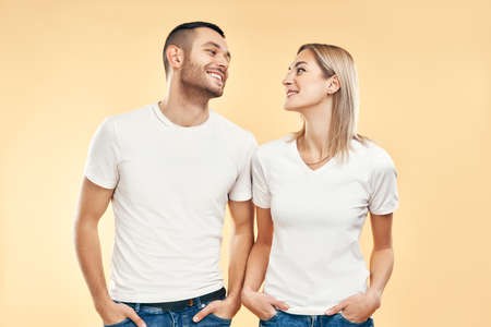 Young happy couple in love look to each other over beige background. Relationship, flirting conceptの写真素材