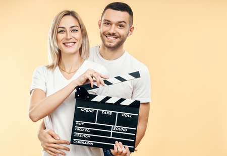 Young happy couple with cinema clapper board. Man hugging a woman with movie clapper board. Cinematography conceptの写真素材