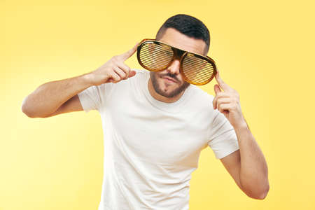 Young man in funny party glasses over yellow background.  Fun conceptの写真素材
