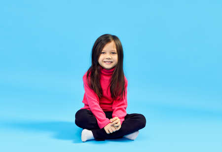 Sweet little girl posing over blue studio backgroundの写真素材