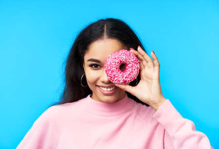 Attractive black woman having fun with donutsの写真素材