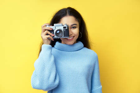 Young beautiful african american woman taking photo with retro cameraの写真素材