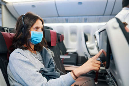 Woman in virus protection face mask sitting in empty airplane