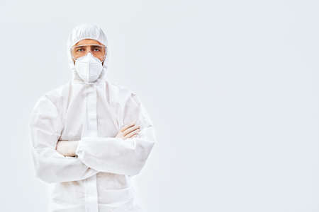 Confident doctor with crossed arms in protective medical suitの写真素材