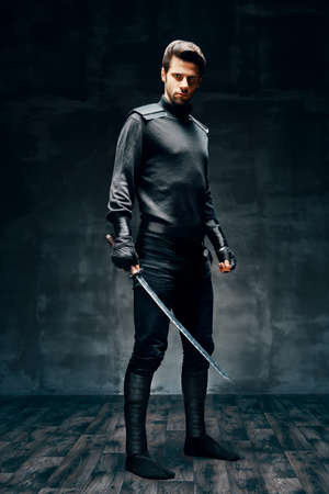 Full length portrait of warrior man posing with a swordの写真素材