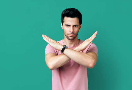 Young handsome man showing stop sign on blue background