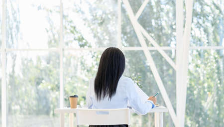 Back view of pretty black businesswoman working with laptop in modern office