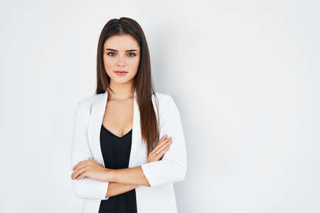 Smiling trendy businesswoman with crossed arms posing on white with copy spaceの写真素材