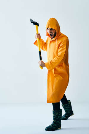 Aggressive man in orange raincoat threaten with axeの写真素材
