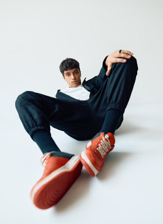 Young trendy mixed race man posing in studio lying on floor on white backgroundの写真素材