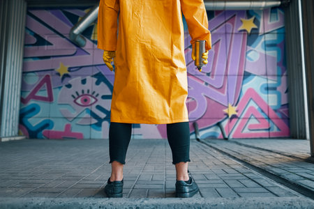 Cropped image of street artist with spray paint can in hand standing near the wallの写真素材