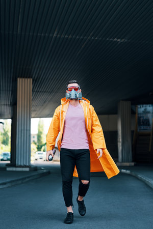 Trendy young man in respirator mask walking down the streetの写真素材