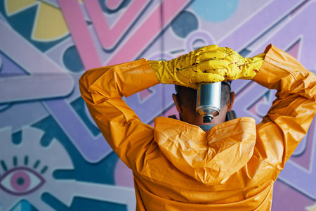 Cropped image of street artist with spray paint can in hand standing near the wall