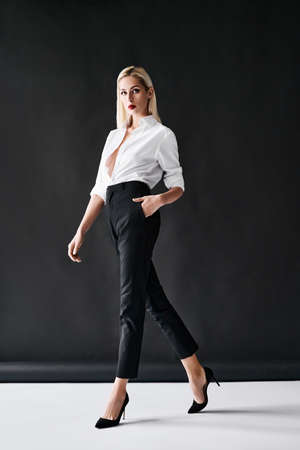 Full length fashion portrait of young stylish woman posing on black background.の写真素材