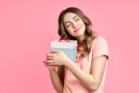 Happy woman holding and hug gift box on pink background.の写真素材