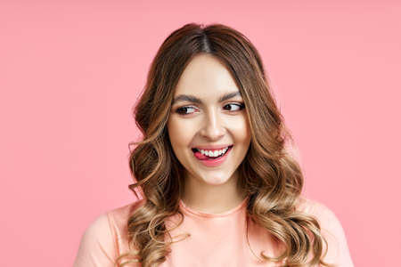 Playful woman showing tongue lookingaside over pink backgroundの写真素材