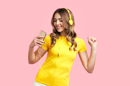Cheerful young woman listening to music with headphones and dancing