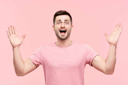 Surprised excited man portrait with arms raisedの写真素材