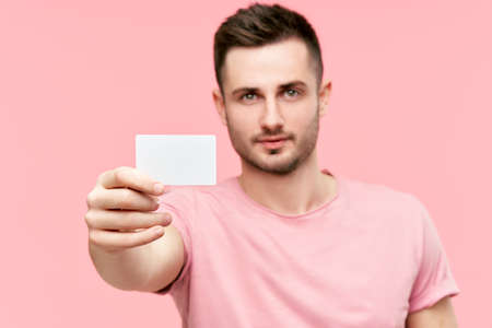 Portrait of young man showing credit card and looking to cameraの写真素材