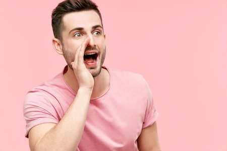 Young handsome man shouting and screaming loud to side with hand on mouth and copy space for text on...