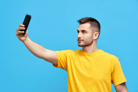 Handsome young man taking selfie over blue backgroundfvg