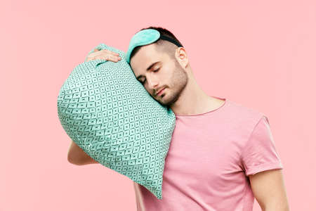 Young handsome man sleeping holding pillow in handsの写真素材