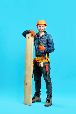 Full length portrait of young handsome carpenter showing thumbs up sign holding pile of lumber woods andの写真素材