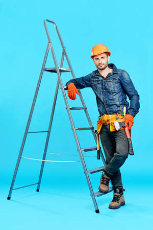 Full length portrait of handsome male construction worker climbing on ladderの写真素材