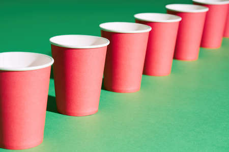 Diminishing perspective of red paper cup in row on green backgroundの写真素材