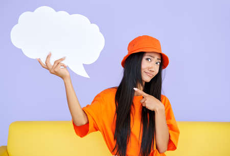Young hipster woman holding empty speech bubble pointing her finger on itの写真素材
