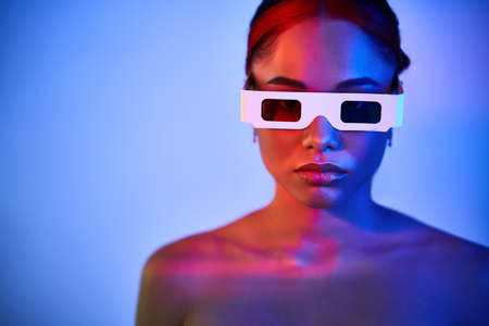 Pretty african american woman wearing 3D glasses in neon light