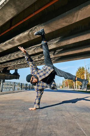 Young man break dancer dancing on urban background performing acrobatic stuntsの写真素材