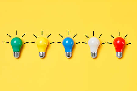 Creative layout with multicolored lightbulbs on yellow background.の写真素材
