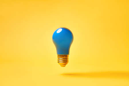 Blue lightbulb levitate on yellow background. Idea and inspiration conceptの写真素材