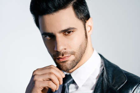 Closeup portrait of handsome trendy man posing on white studio background