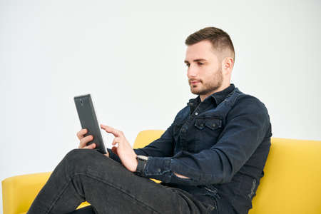 Young Man looking at digital tablet sitting on bright sofa