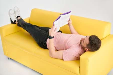 Man relaxing on sofa reading book