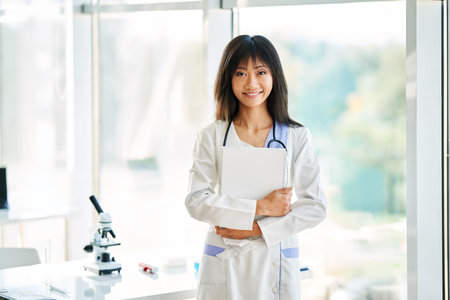 Smiling female asian doctor witn stethoscope wearing in lab coat looking to cameraの写真素材