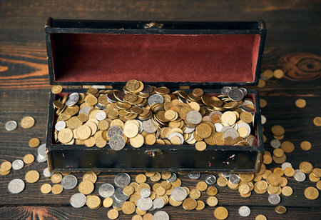 Chest filled with coins of Ukraine on wooden backgroundの写真素材