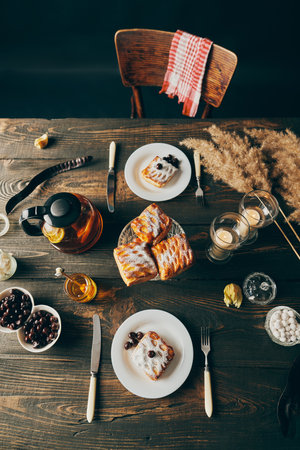 Top view of beautifully served table decorated in rustic style with homemade pastries, teapot and candlesの写真素材